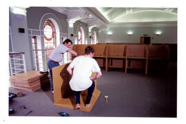Two workmen erecting carrels.