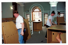 Three workmen erecting carrels.