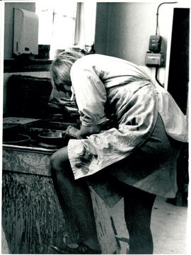 Crouched over potter’s wheel.